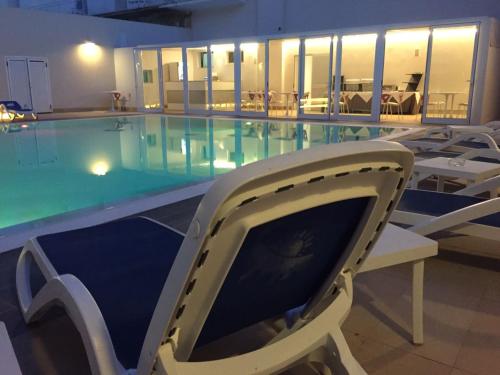 a swimming pool with chairs in a building at Hotel Miramare in Marina di Ragusa