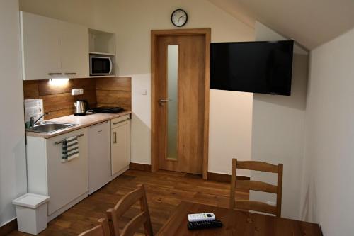 a kitchen with a table and a small kitchen with a clock at Penzion U Hujňáků in Rohatec