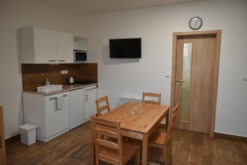 a kitchen with a wooden table and a table and chairs at Penzion U Hujňáků in Rohatec