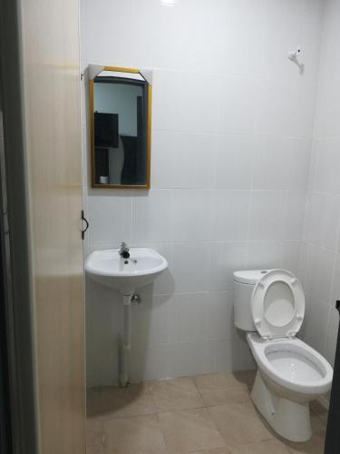 a bathroom with a toilet and a sink and a mirror at Axis Hotel in Taiping