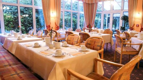 a dining room with tables and chairs and windows at AMBER HOTEL Chemnitz Park in Chemnitz