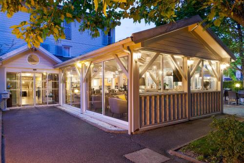 a pavilion with glass doors on a building at Hotel Acadie Les Ulis in Les Ulis