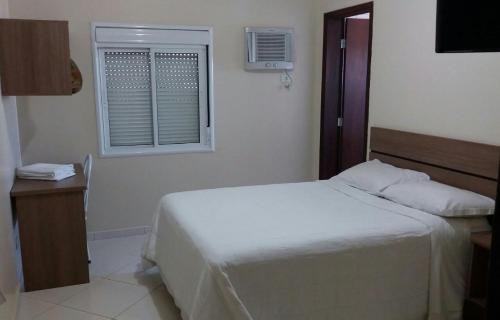 1 dormitorio con cama blanca y ventana en Imbau Palace Hotel, en Imbau