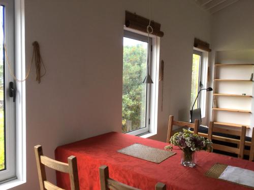a dining room table with a red tablecloth and two windows at Quinta da Falésia - Casa Amarela in Ponta Delgada