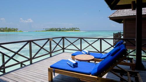 two blue lounge chairs on a deck near the water at Sun Siyam Olhuveli in South Male Atoll