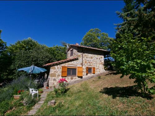una pequeña casa de piedra en una colina con sombrilla en Belvilla by OYO Baita del Por Azzolo, en Seggiano
