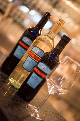 three bottles of wine sitting on a table with a glass at Hotel Vela Azzurra in Malcesine