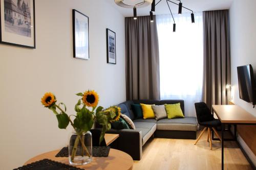 a living room with a couch and a table with a vase of sun flowers at Aparthotel BC 29 Residence in Kraków