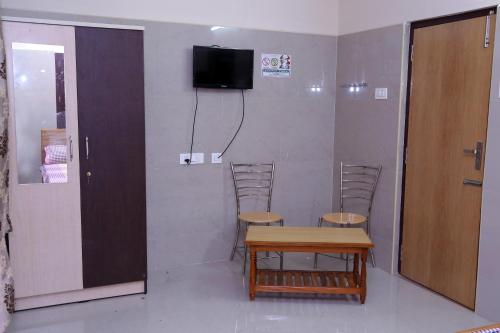 Zimmer mit 2 Stühlen, einem Tisch und einem TV in der Unterkunft SGRT Residency in Vellore