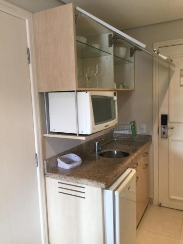 a small kitchen with a sink and a microwave at Flat Partic Hotel Jurere Beach Village in Florianópolis