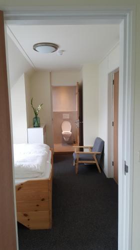 a bedroom with a bed and a chair and a toilet at Rufus aan het water in Broek