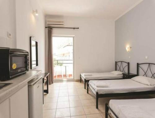 a room with three beds and a tv in it at Quayside Village Hotel in Kavos