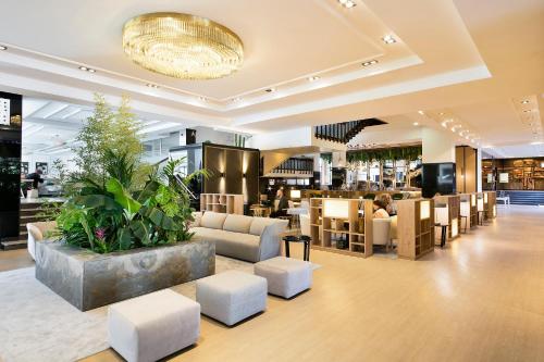 a lobby with couches and chairs and a restaurant at Melia Barajas in Madrid