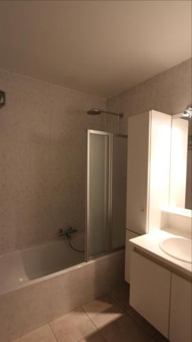 La salle de bains est pourvue d'une baignoire blanche et d'un lavabo. dans l'établissement Residentie Gaudi, à Nieuport