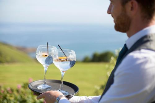 a man holding two wine glasses on a tray at Talland Bay Hotel, Looe in Talland
