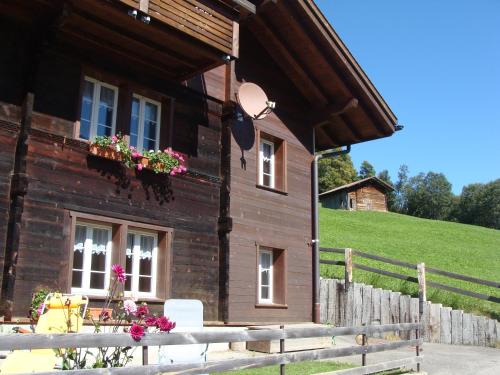ein Holzhaus mit Blumen an den Fenstern in der Unterkunft Chalet Sunnegg in Adelboden