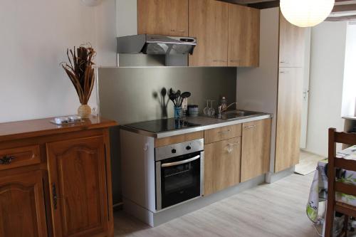 une cuisine avec des armoires en bois et un four à plaques de cuisson dans l'établissement Un petit coin de paradis, à Champigny-sur-Veude