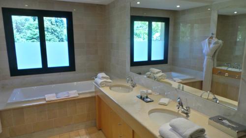a bathroom with a tub and a sink and a mirror at Hotel & Spa Le Pavillon in Charbonnières-les-Bains