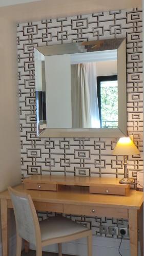 a mirror on a wall next to a wooden desk at Hotel & Spa Le Pavillon in Charbonnières-les-Bains