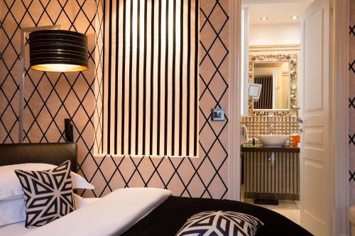 a bedroom with a bed and a mirror and a sink at Hotel Ares Eiffel in Paris
