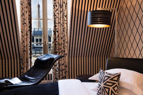 a room with a bed and a chair and a window at Hotel Ares Eiffel in Paris
