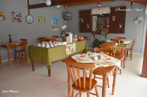 a dining room with a table and chairs and a kitchen at Pousada Açai in Paraty