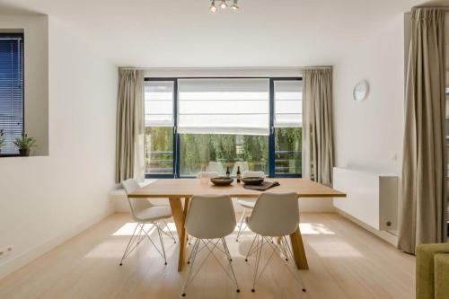 a dining room with a wooden table and white chairs at The Livorno in Brussels
