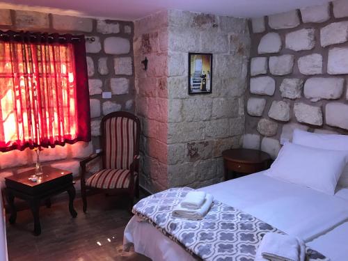 a bedroom with a bed and a chair and a window at Mensa Christi Guesthouse in Nazareth