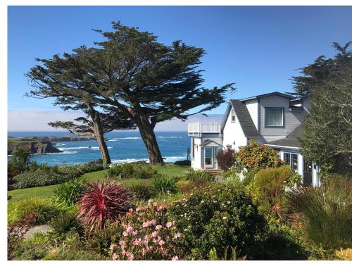 a house with a tree and the ocean in the background at Agate Cove Inn in Mendocino