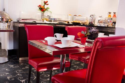 a table with four red chairs and a counter at Hotel Ares Eiffel in Paris