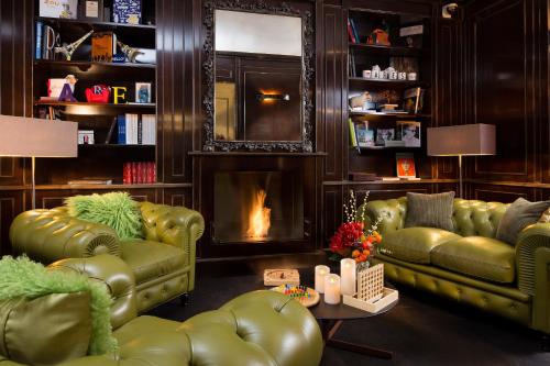 a living room with two green leather couches and a fireplace at Hotel Ares Eiffel in Paris