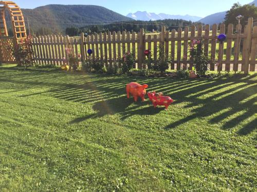 a toy cow in the grass next to a fence at Pension und Apartments Landhaus Marie in Leutasch