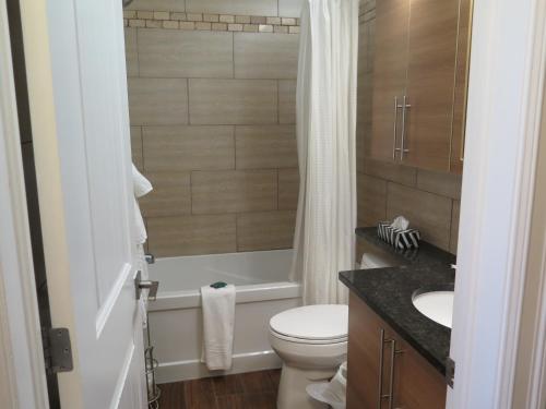 a bathroom with a toilet and a tub and a sink at Western Hotel & Executive Suites in Guelph