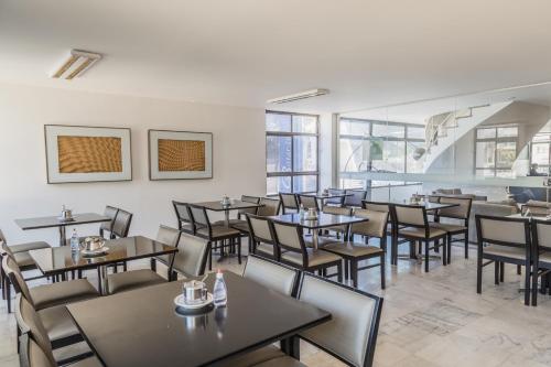 uma sala de jantar com mesas, cadeiras e janelas em Bittar Inn em Brasília