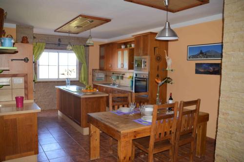 una cocina con mesa de madera y sillas. en VIVIENDA VACACIONAL Casa Tajinaste, en La Listada