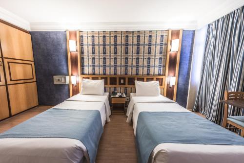 a row of three beds in a hotel room at Monumental Bittar Hotel in Brasilia