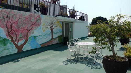 a table and chairs in front of a wall with a mural at Hotel Aurora in Oaxaca City