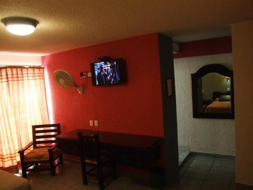 a living room with a tv on a red wall at Hotel Aurora in Oaxaca City