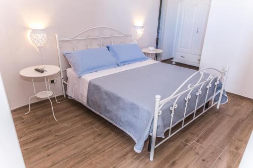 a bedroom with a white bed with blue sheets and two tables at B&B Amelì in Bari