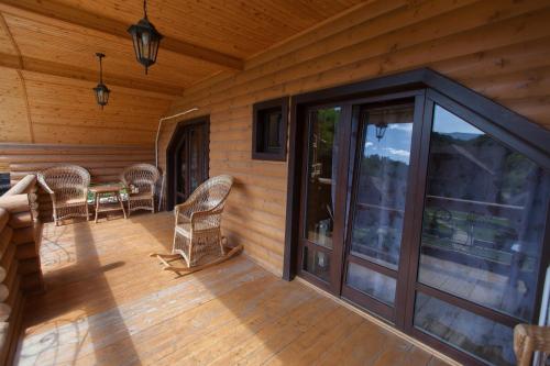 a screened in porch of a log cabin with a table and chairs at Oasis Karpat in Polyana
