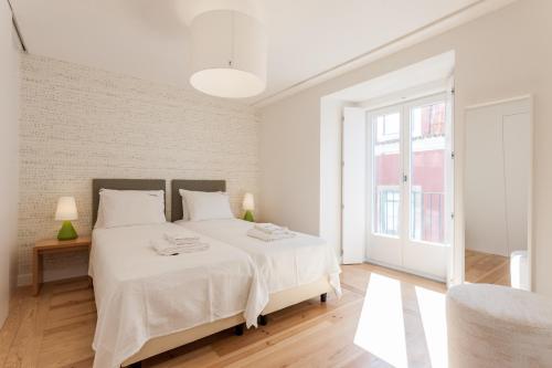 - une chambre blanche avec un grand lit et une fenêtre dans l'établissement FLH Portas do Sol Cozy Flat, à Lisbonne