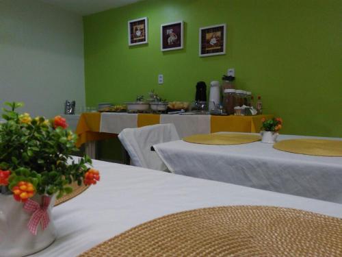 Habitación verde con mesas, ropa de cama blanca y flores en Pousada das Maracanãs, en Maracanaú