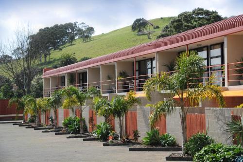 a building with trees and a hill in the background at Ascot Epsom Motel in Auckland