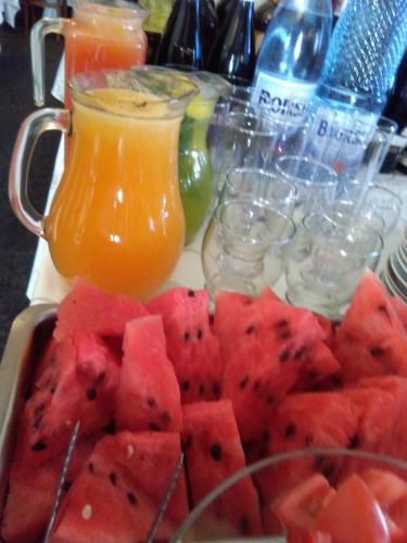 a plate of watermelon and a pitcher of orange juice at VILA Corviniana in Hunedoara