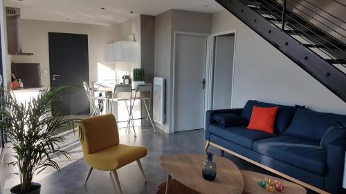 a living room with a blue couch and a table at Le Loft de Genas entre Eurexpo et St Exupéry in Genas