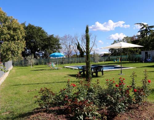 a park with a table and umbrella and a pool at Parcoverdepino in Bastia Umbra