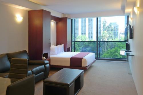 een hotelkamer met een slaapkamer met een bed en een bank bij Suites Capri Reforma Ángel 380 in Mexico-Stad
