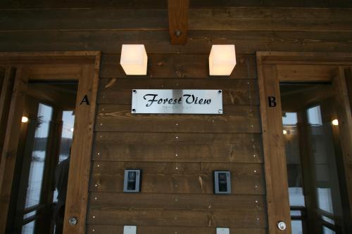 a sign on a wooden wall with a forest sign on it at Forest View in Furano