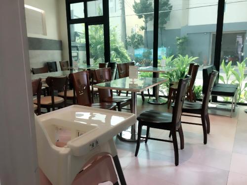 a dining room with tables and chairs and windows at Wei Feng Exquisite Motel Pintung Branch in Pingtung City