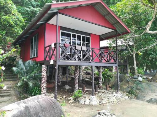 a small red and white house with a balcony at Simukut Place in Kampong Pasir Sanang Burong